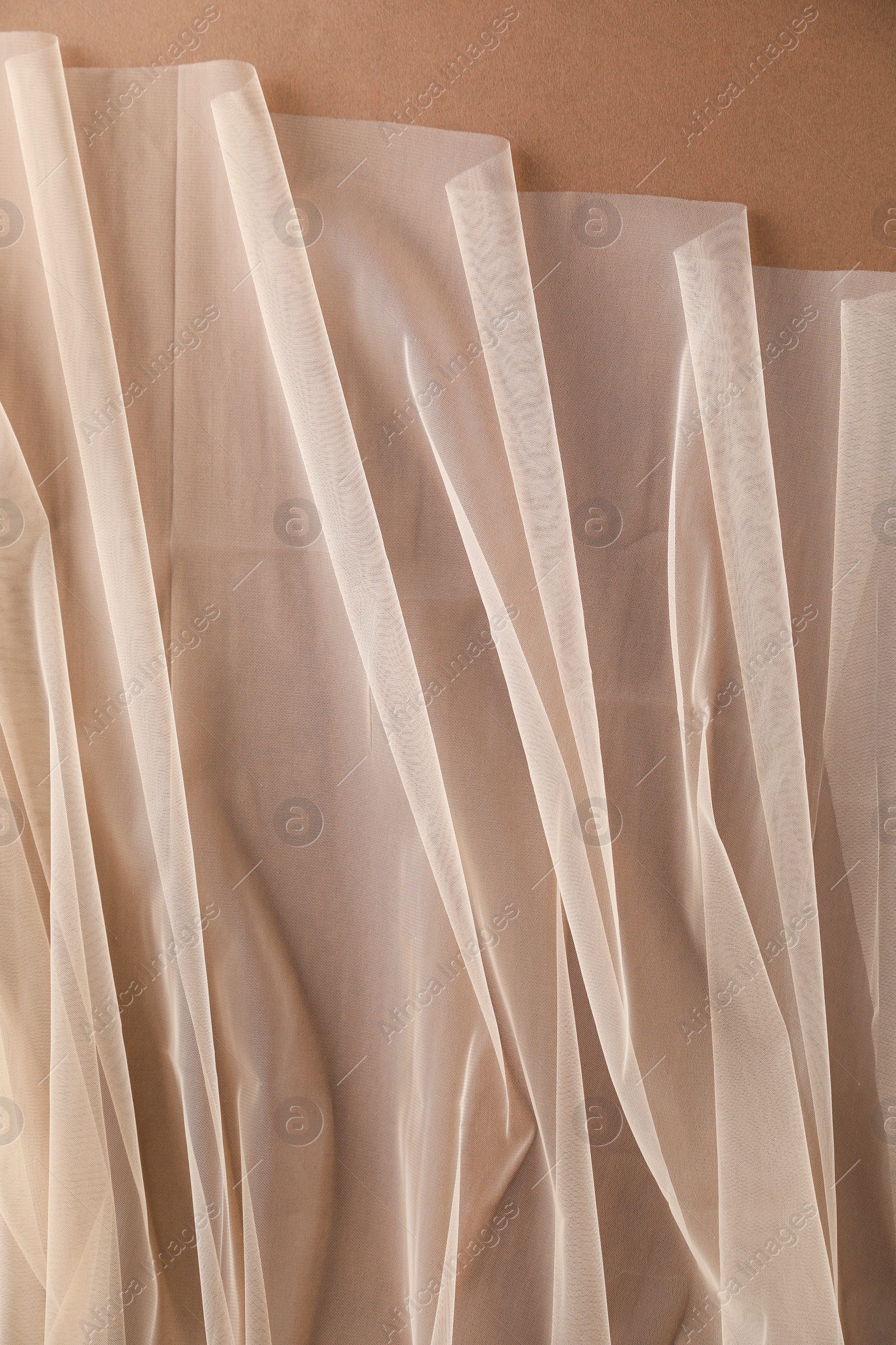 Photo of Beautiful tulle fabric on brown background, top view