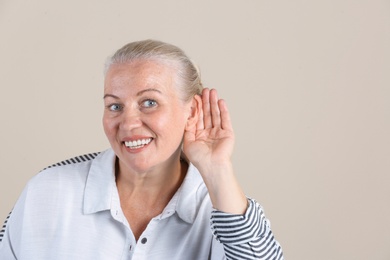 Mature woman with hearing problem on light background