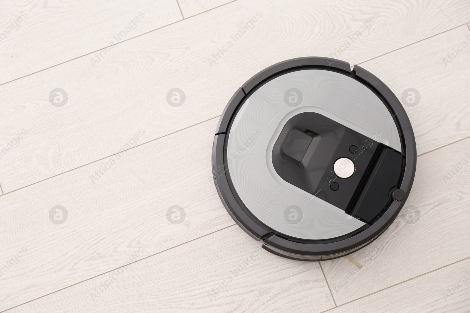 Photo of Modern robotic vacuum cleaner on wooden floor, top view. Space for text