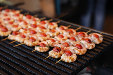 Photo of Delicious fresh shrimp skewers with cherry tomatoes on grill, closeup