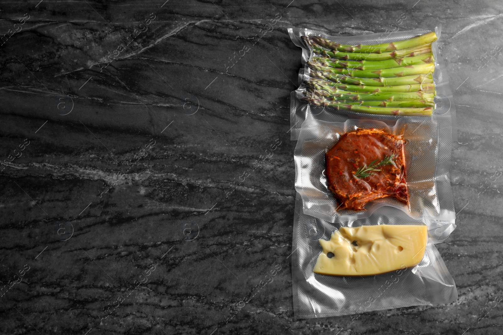 Photo of Different food products in vacuum packs on black marble table, flat lay. Space for text