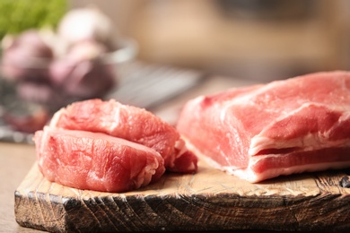 Fresh raw meat on wooden board in kitchen, closeup