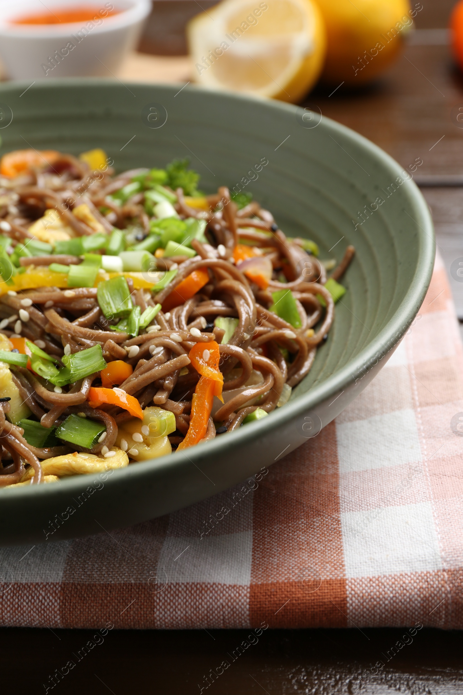 Photo of Stir-fry. Delicious cooked noodles with chicken and vegetables in bowl on table, closeup