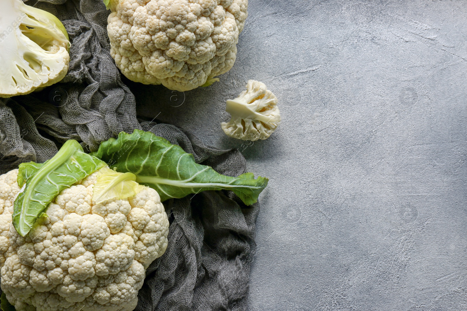 Photo of Fresh whole and cut cauliflowers on grey textured background, top view. Space for text