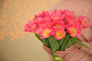 Photo of Girl holding spring tulips on blurred background, closeup with space for text. International Women's Day