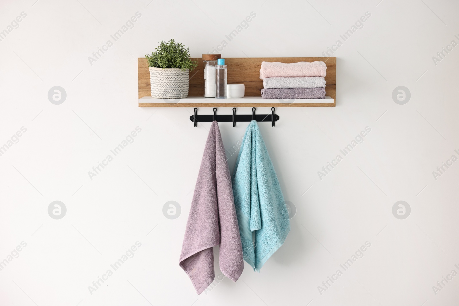 Photo of Clean towels, houseplant and toiletries on shelf indoors