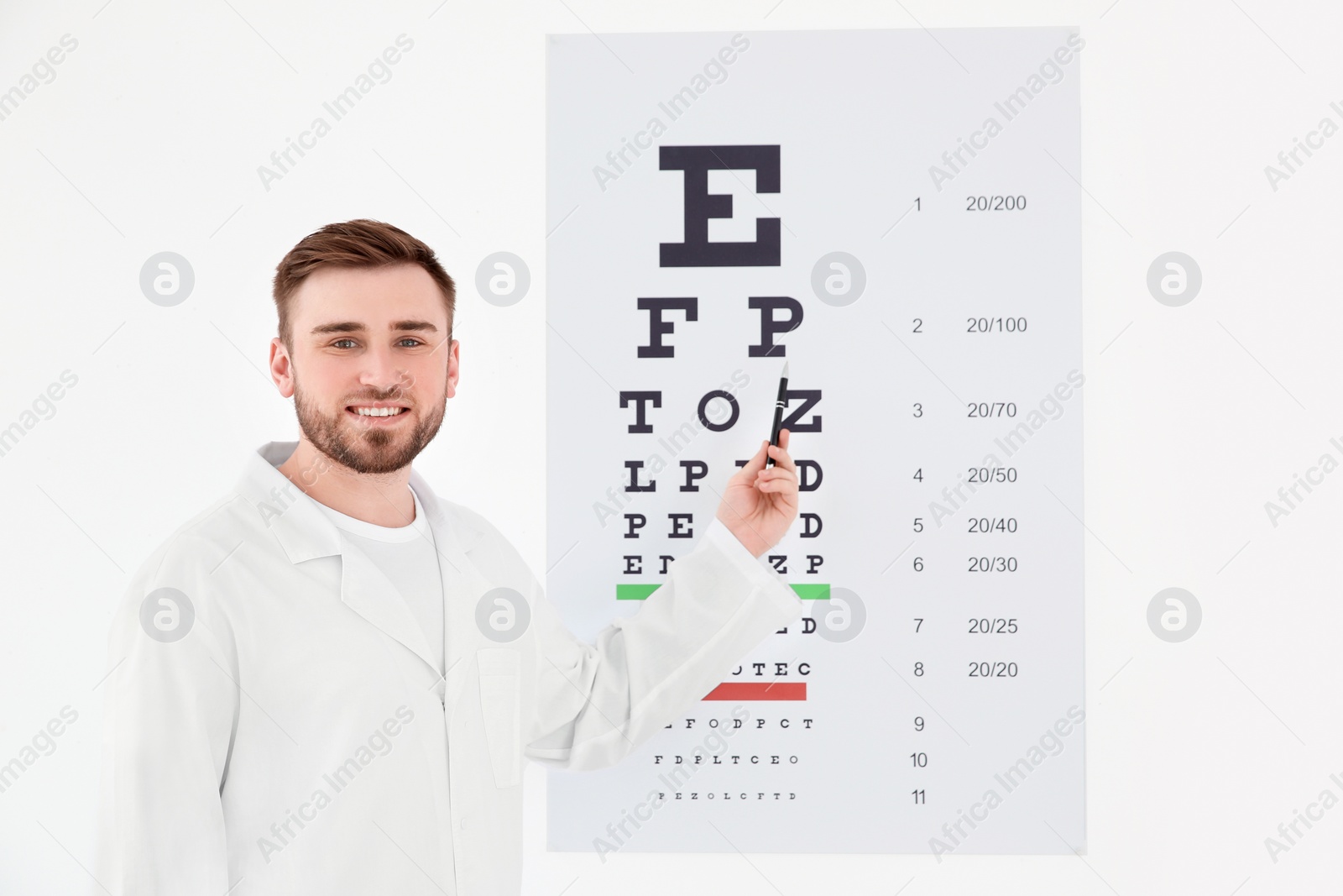 Photo of Young male ophthalmologist near eye chart in clinic