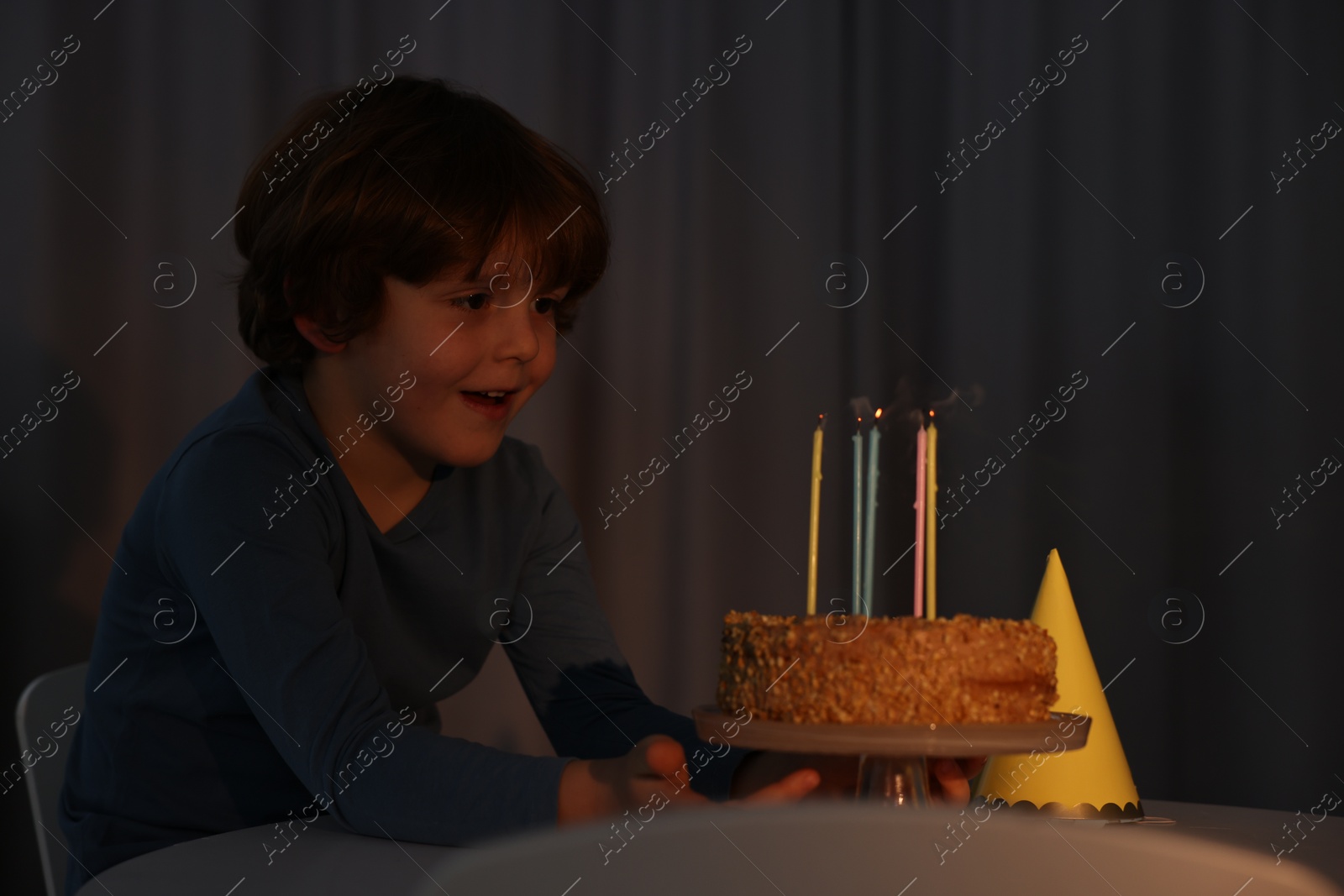 Photo of Cute boy with birthday cake at table indoors