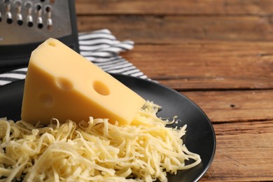 Photo of Grated and whole piece of cheese on wooden table, closeup. Space for text