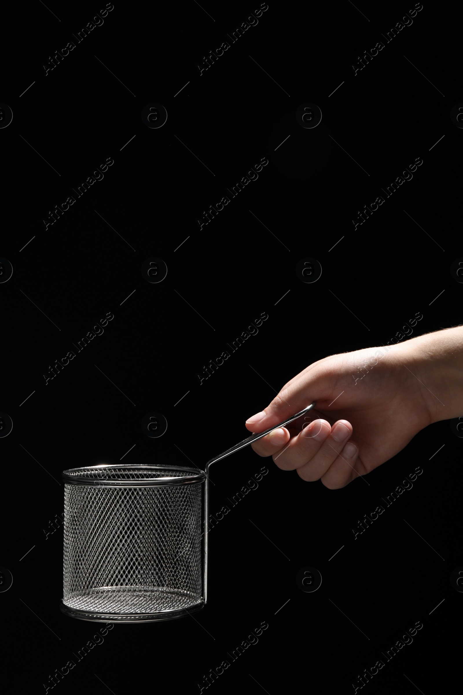 Photo of Woman holding metal basket for French fries on black background, closeup