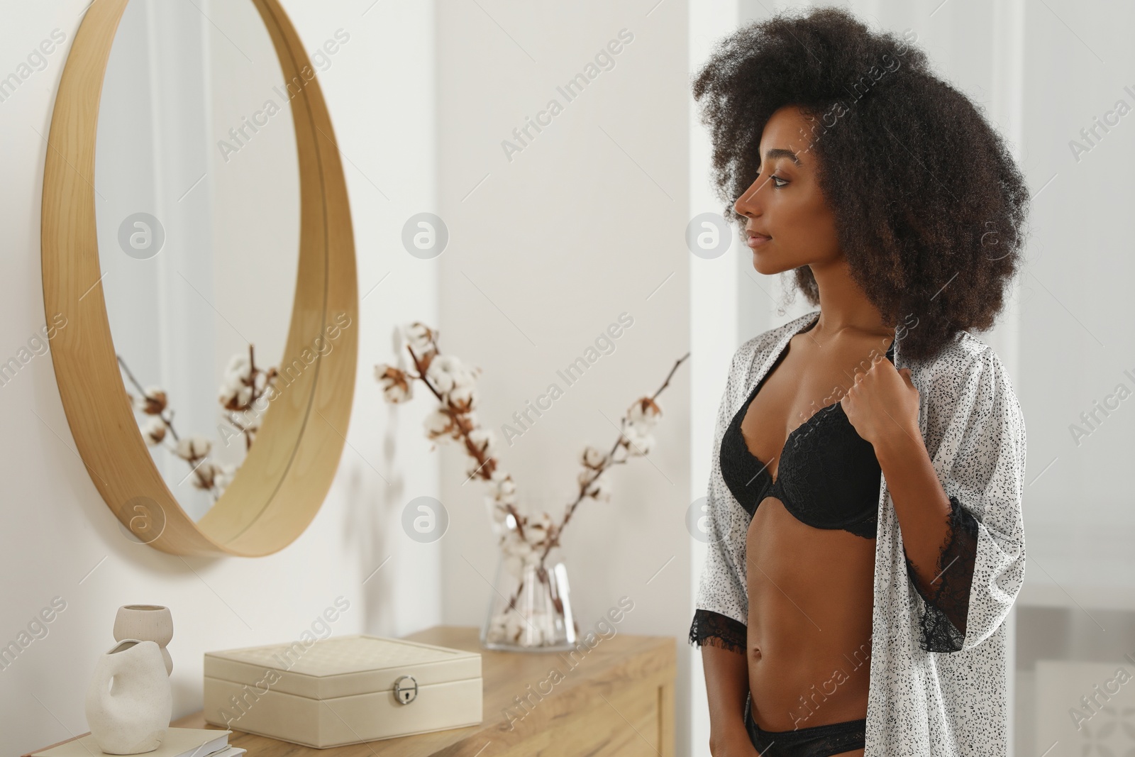 Photo of Beautiful woman in elegant black underwear and robe near mirror indoors