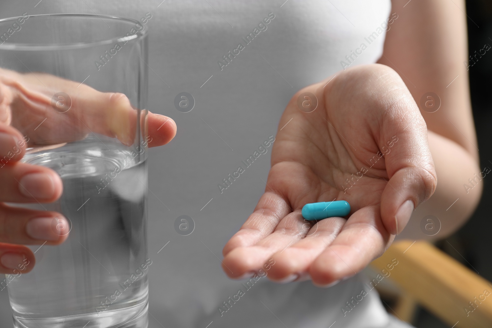 Photo of Woman holding glass of water and pill, closeup