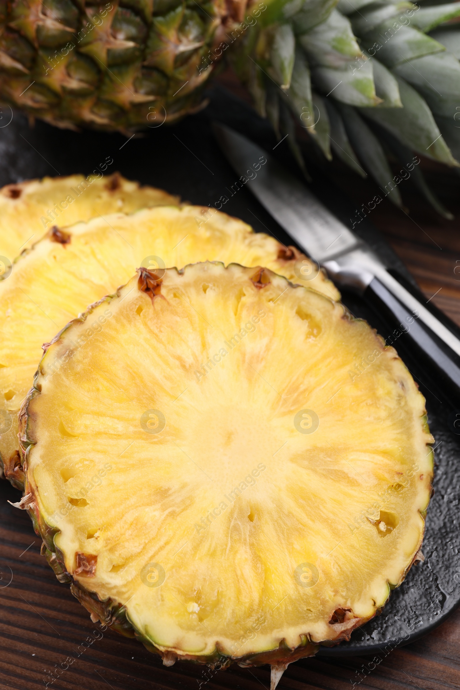 Photo of Pieces of tasty ripe pineapple on wooden table, closeup