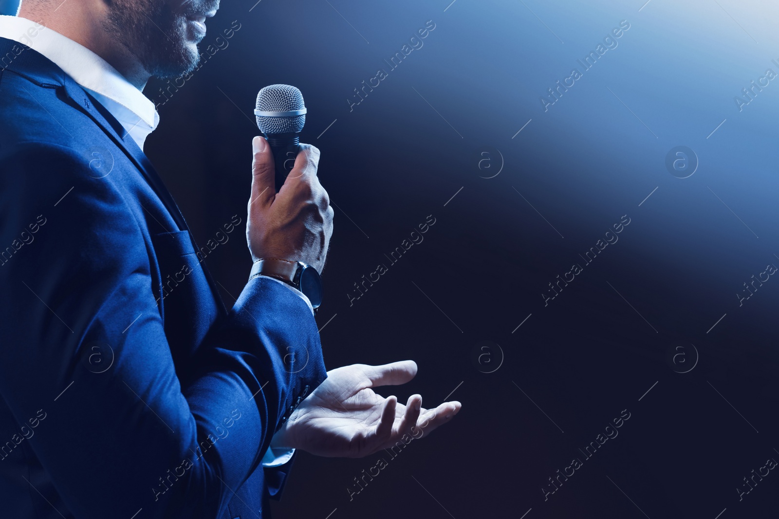 Photo of Motivational speaker with microphone performing on stage, closeup. Space for text