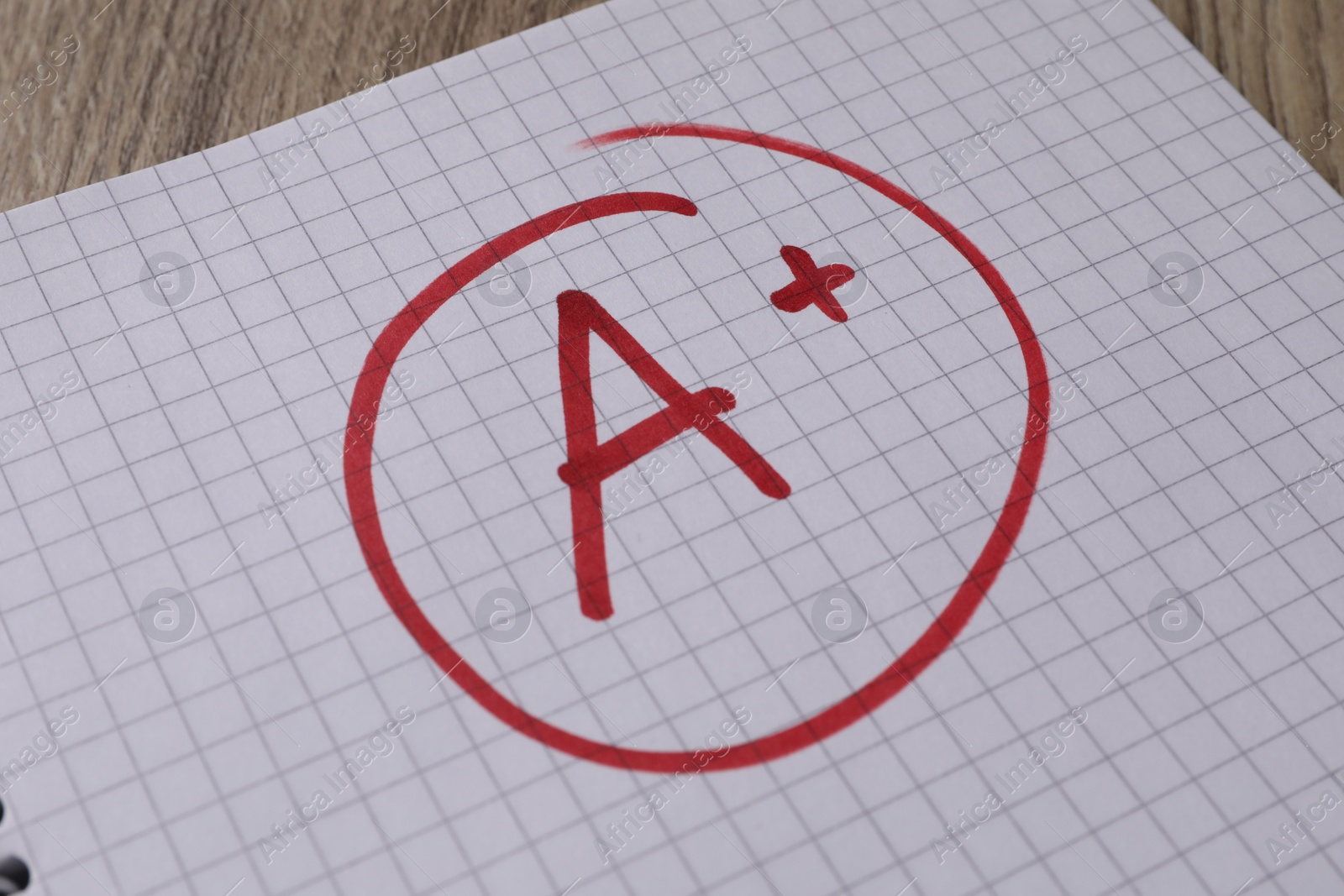 Photo of School grade. Red letter A with plus symbol on notebook paper, closeup