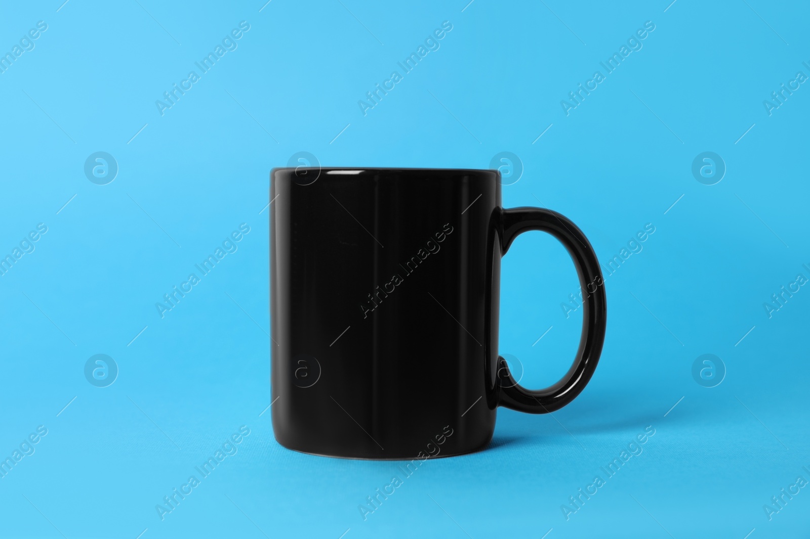One black ceramic mug on light blue background Photo of One black ceramic mug on light blue background