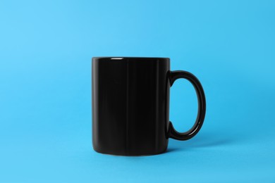 Photo of One black ceramic mug on light blue background