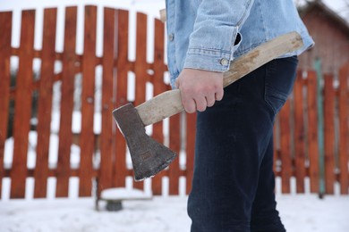 Photo of Man with metal axe outdoors on winter day, closeup. Space for text