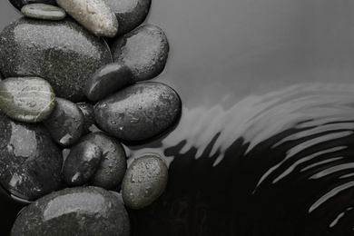 Photo of Spa stones in water, top view with space for text. Zen lifestyle