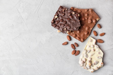 Photo of Different chocolate bars with nuts on grey background, top view