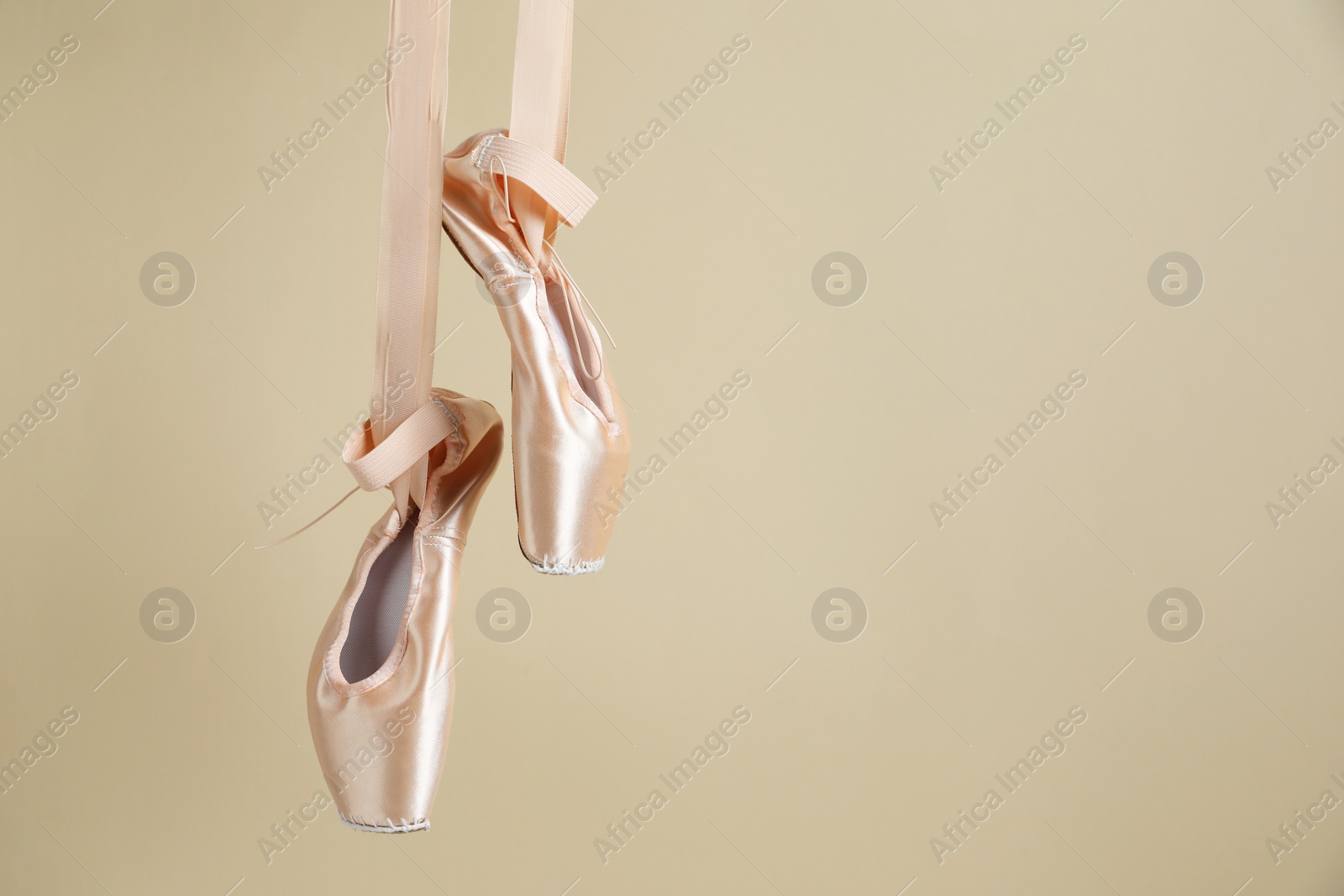 Photo of Ballet shoes. Elegant pointes hanging on beige background. Space for text