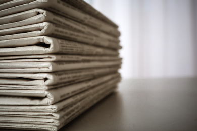 Image of Stack of newspapers on grey table, space for design. Journalist's work