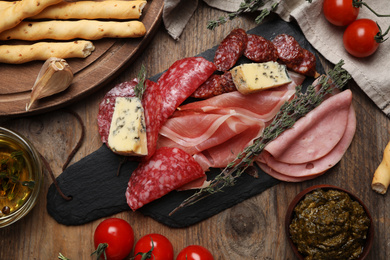 Photo of Tasty ham with other delicacies served on wooden table, flat lay