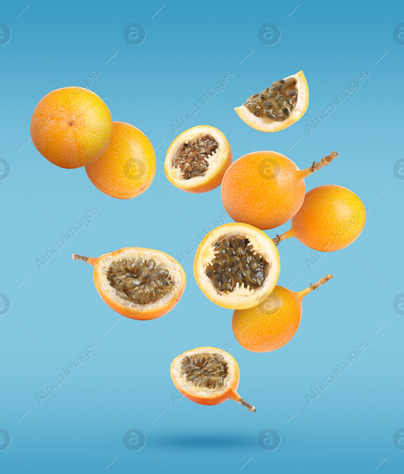 Image of Delicious ripe granadillas falling on light blue background