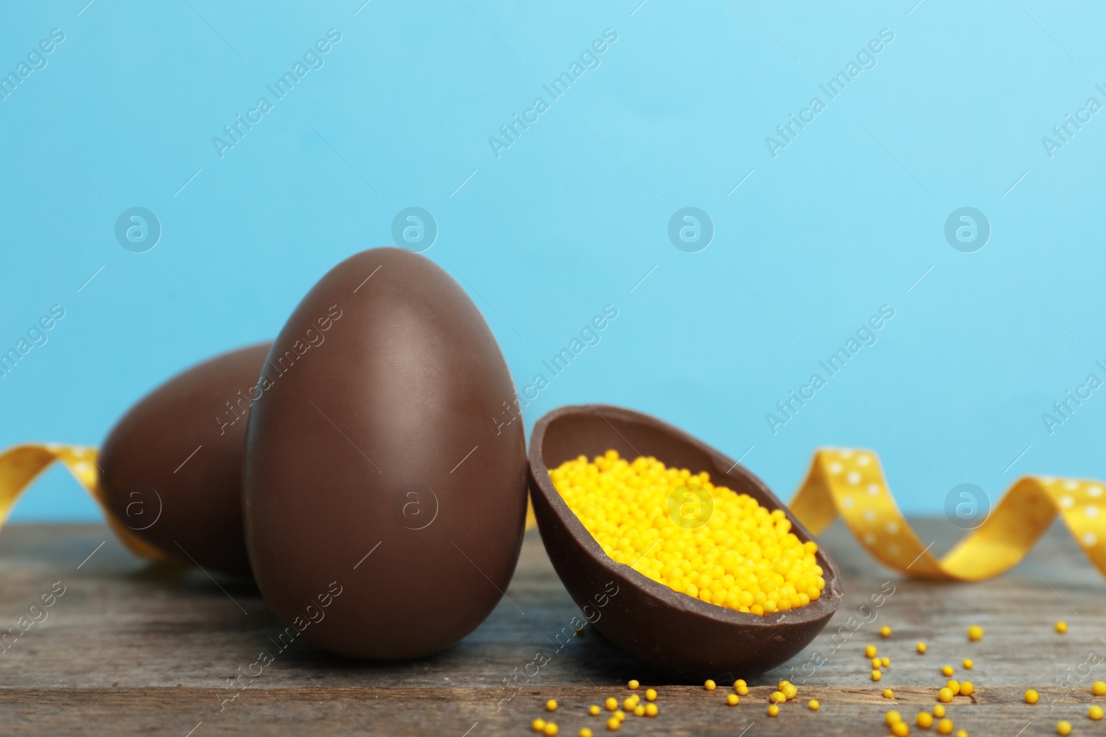 Photo of Composition with chocolate Easter eggs on table against color background. Space for text