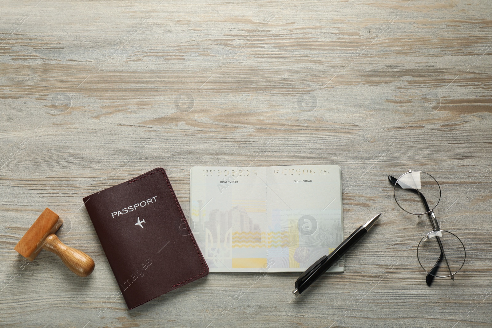 Photo of Moldova, Ceadir-Lunga - June 13, 2022: Flat lay composition with stamp, passports, pen and glasses on wooden table. Space for text