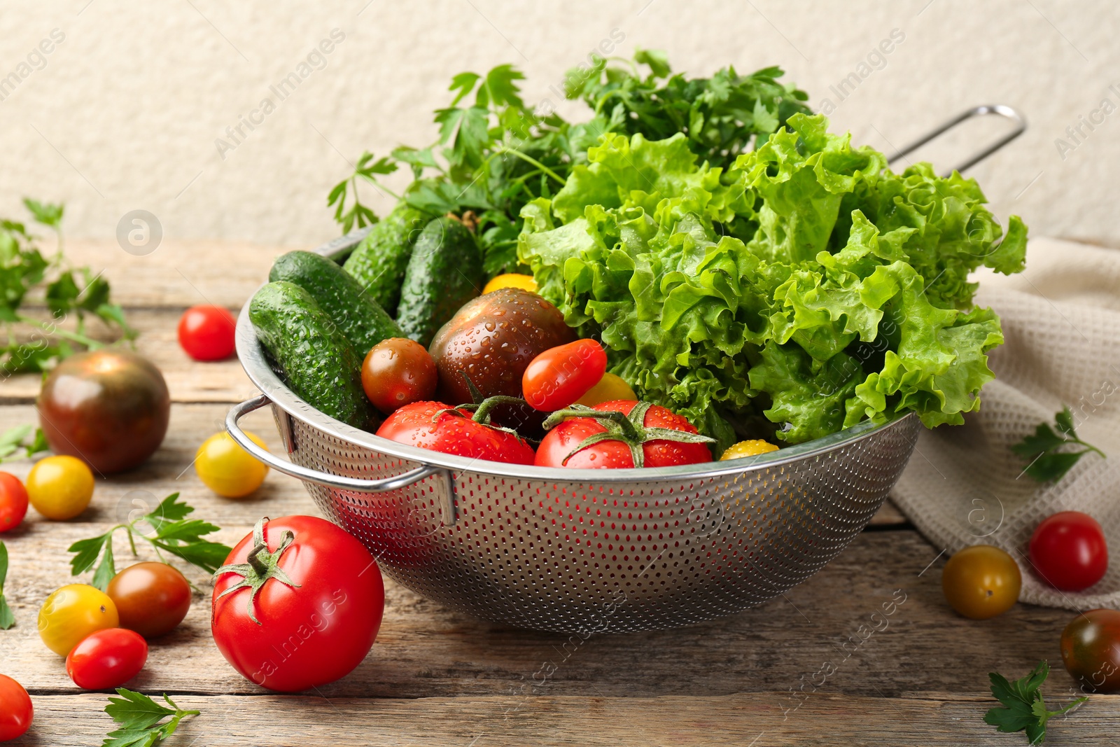 Photo of Wet vegetables in colander on wooden table, closeup