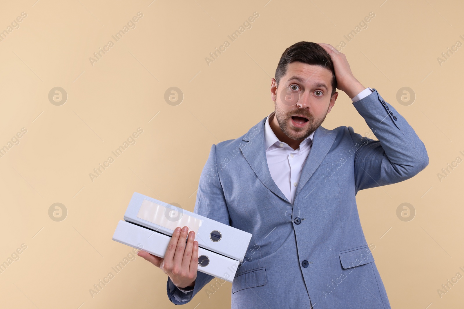 Photo of Emotional accountant with folders on beige background. Space for text