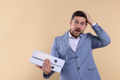 Photo of Emotional accountant with folders on beige background. Space for text
