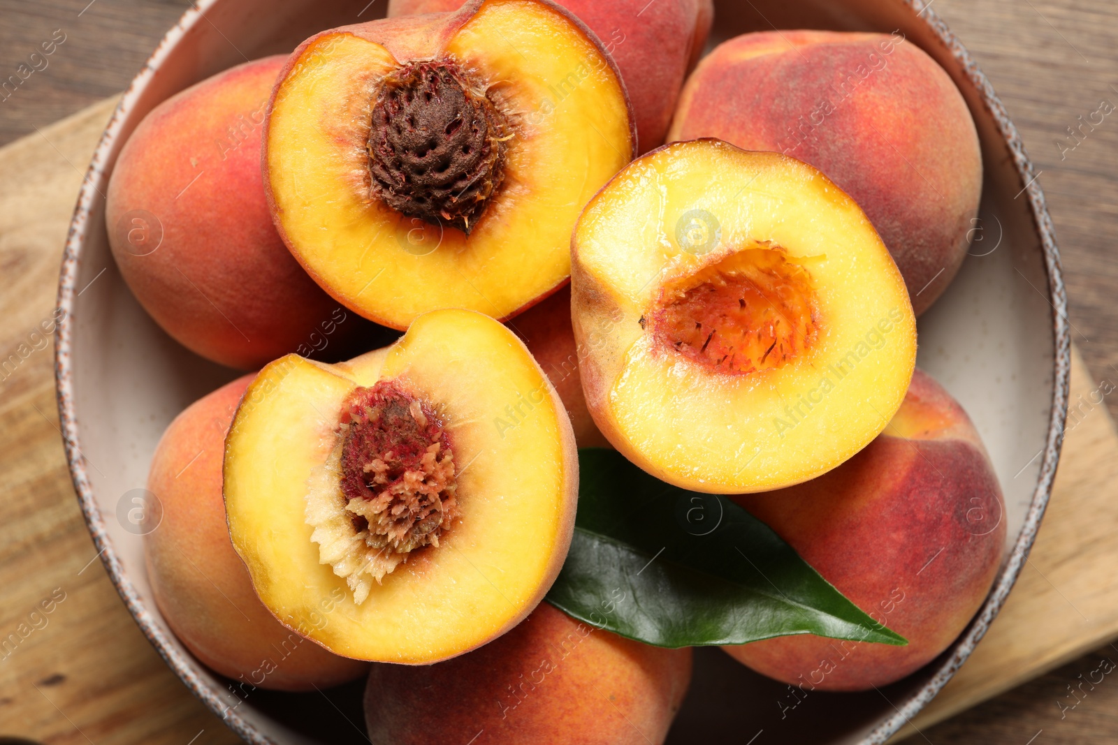 Photo of Plate with delicious juicy peaches and leaf on wooden table, top view