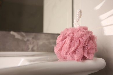 Photo of Pink shower puff on washbasin in bathroom, closeup. Space for text