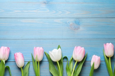 Photo of Beautiful pink spring tulips on light blue wooden background, flat lay. Space for text