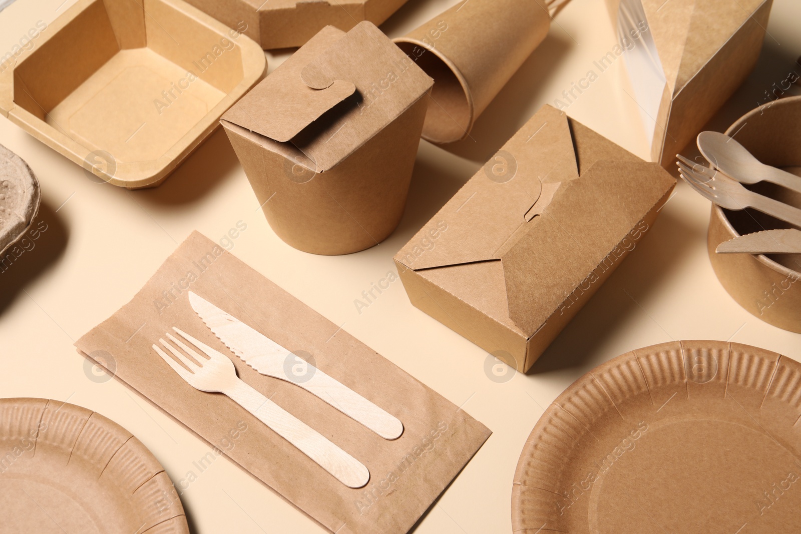 Photo of Eco friendly food packaging. Paper containers and tableware on beige background