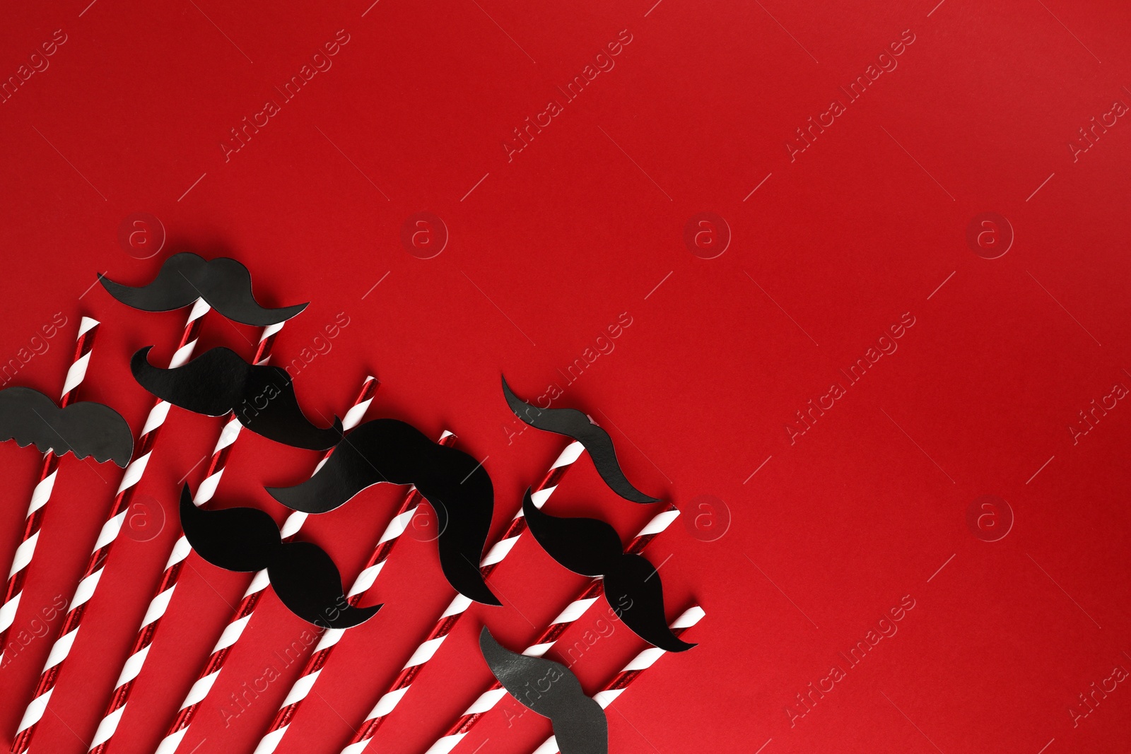 Photo of Fake paper mustaches with party props on red background, flat lay. Space for text