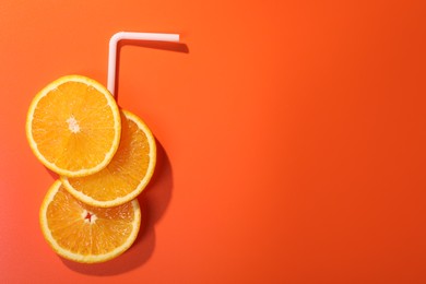 Photo of Slices of juicy orange and straw on terracotta background, top view. Space for text