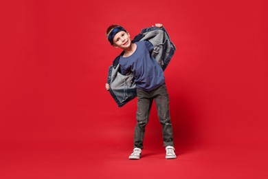 Photo of Happy little boy dancing on red background