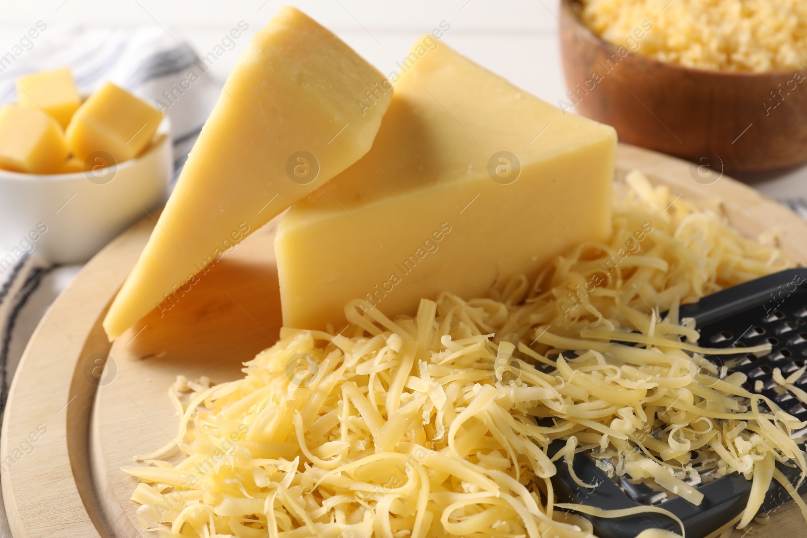 Photo of Grated and whole pieces of cheese on board, closeup