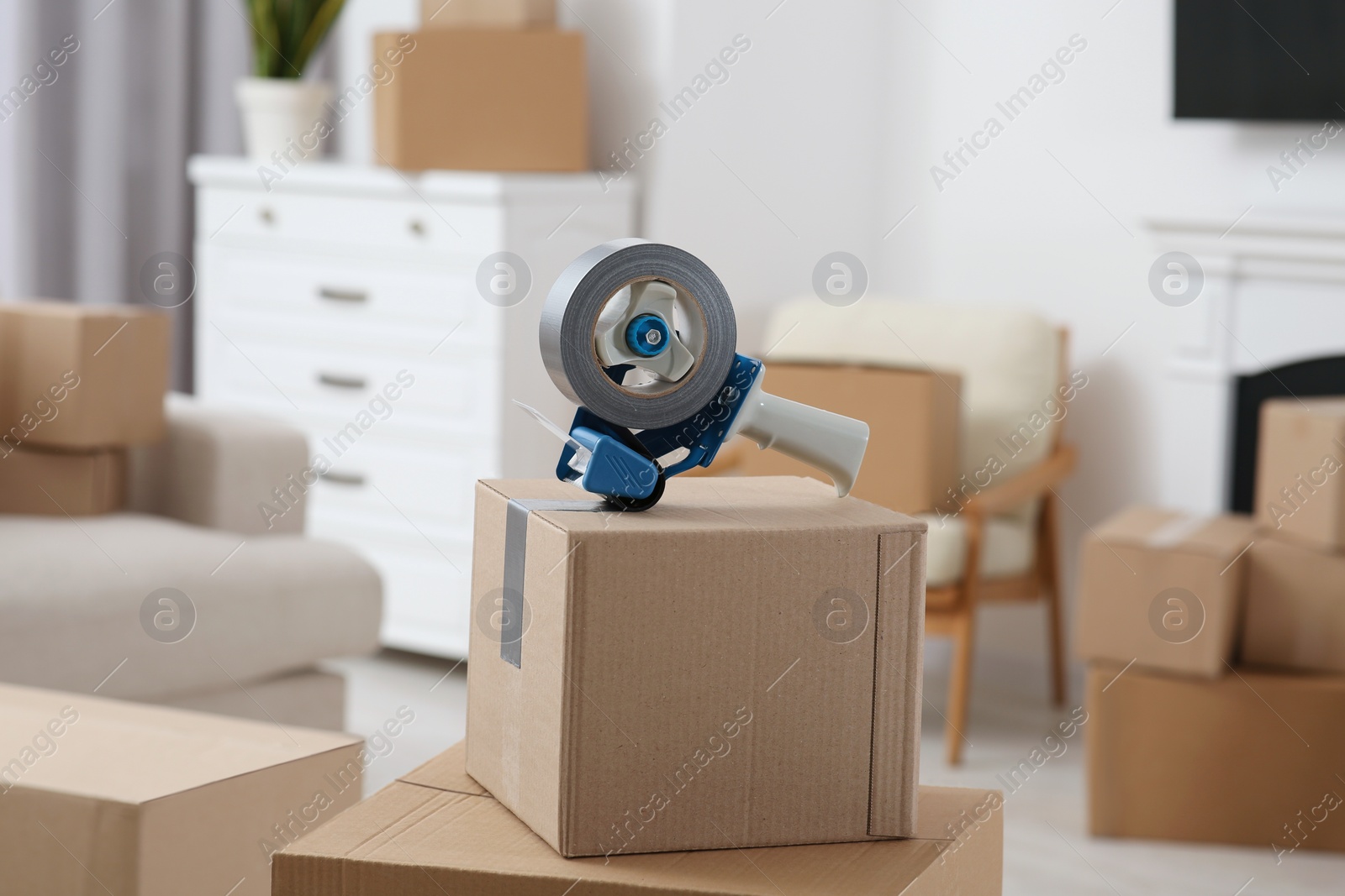 Photo of Dispenser with roll of adhesive tape on box indoors