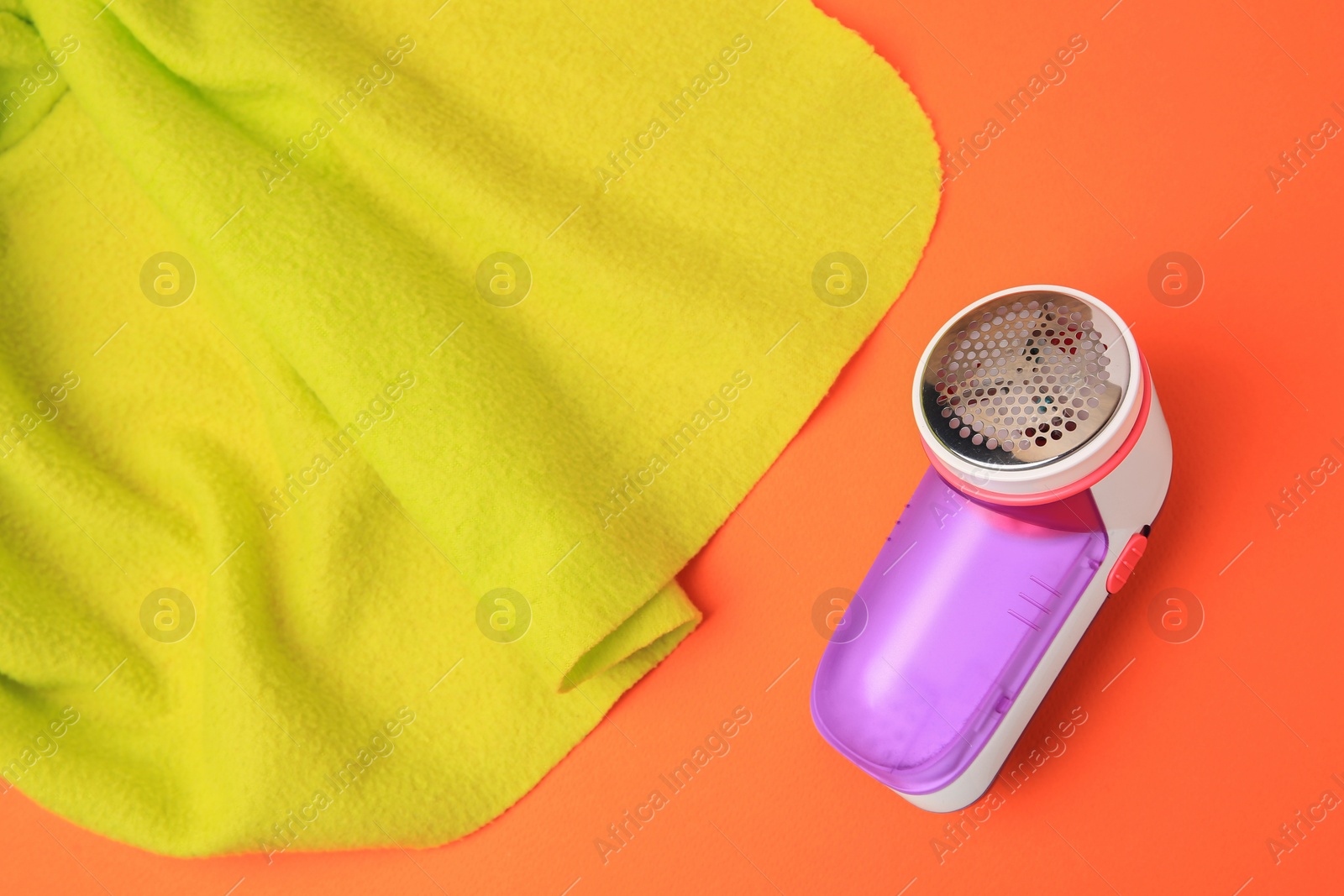 Photo of Fabric shaver and light green cloth on orange background, above view