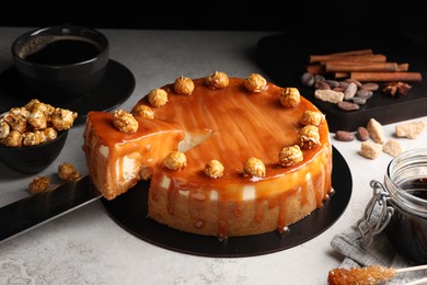 Taking piece of delicious caramel cheesecake with popcorn on light grey table