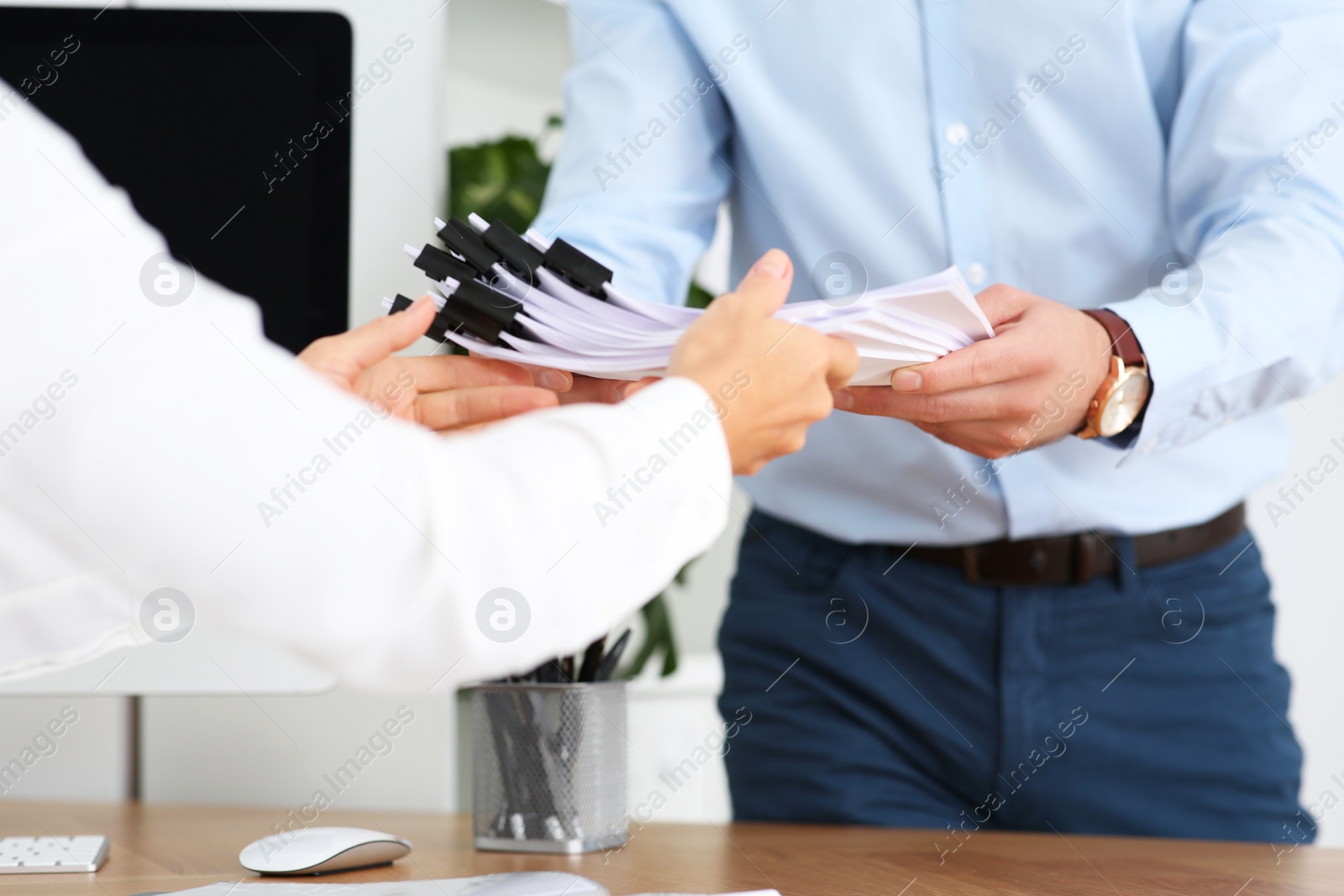 Photo of Man giving documents to colleague in office, closeup