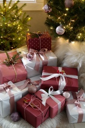 Photo of Gift boxes under small and big Christmas trees indoors