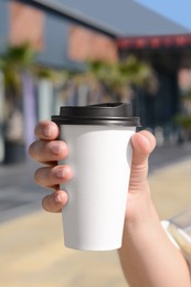 Photo of Woman holding takeaway coffee cup outdoors, closeup