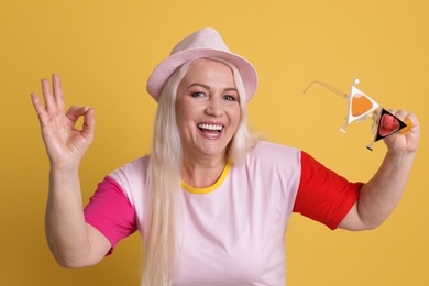 Portrait of mature woman in hipster outfit on color background