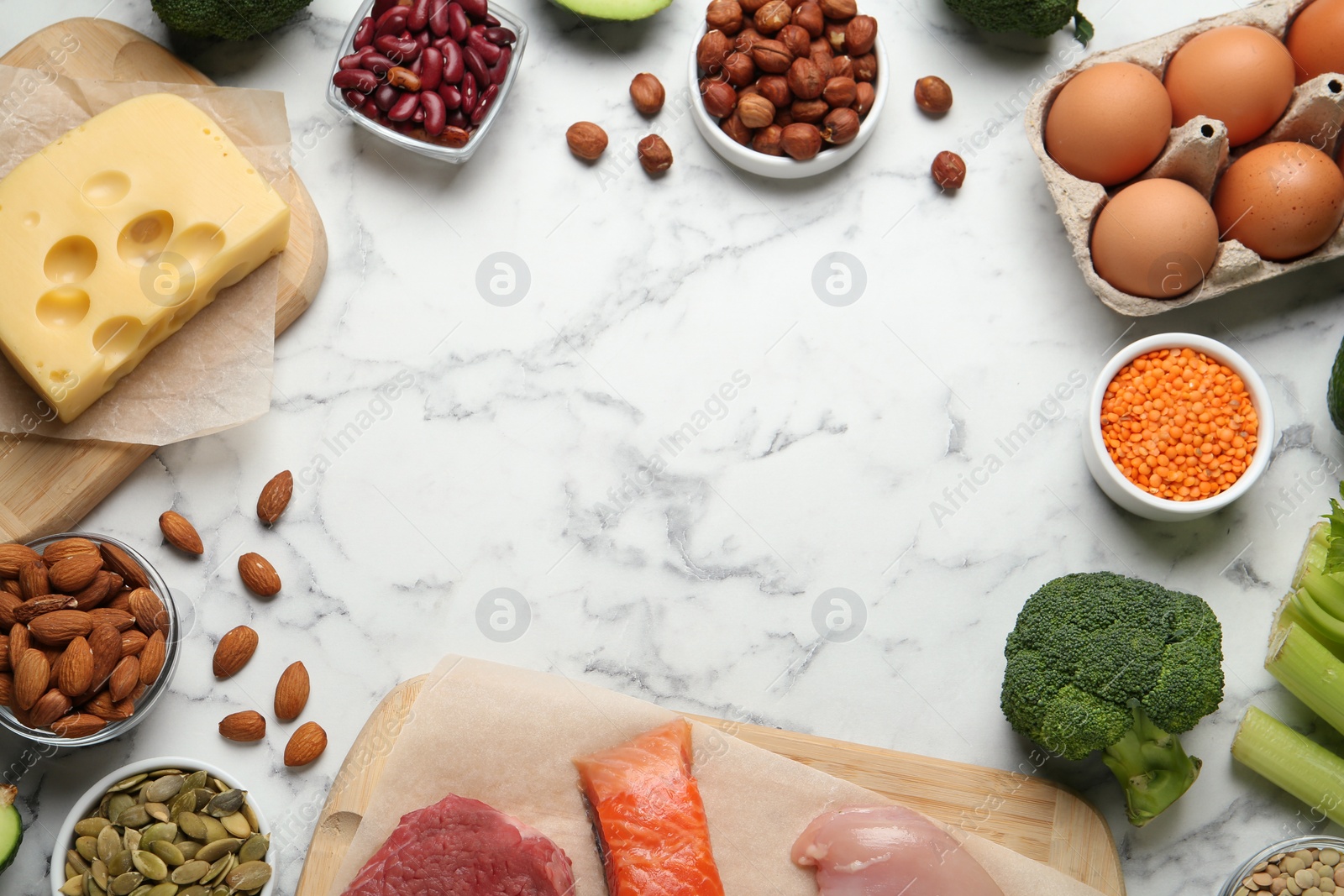 Photo of Frame with different fresh products on white marble table, flat lay. Sources of essential amino acids