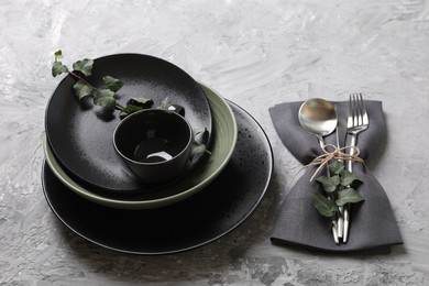 Photo of Stylish table setting. Dishes, cutlery, napkin and floral decor on grey surface
